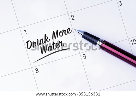 The words Drink More Water on a calendar planner to remind you an important appointment with a pen on isolated white background. New Year concepts of goal and objective.