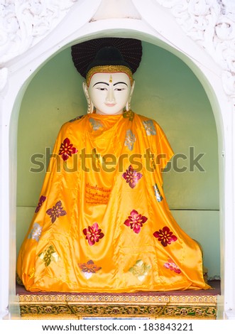 Buddha image with an orange robe at the Shwedagon Pagoda in Yangon, the capital of Republic of the Union of Myanmar.