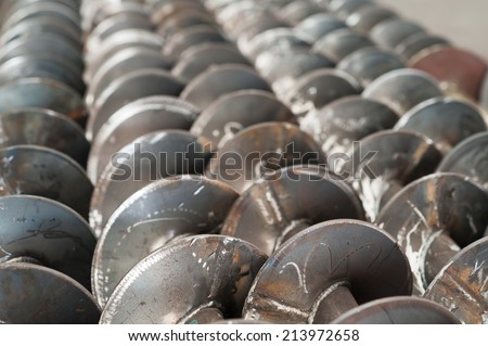 Unfinished screw conveyor parts at a factory. Very shallow depth of field with the nearest part of the screws in focus.