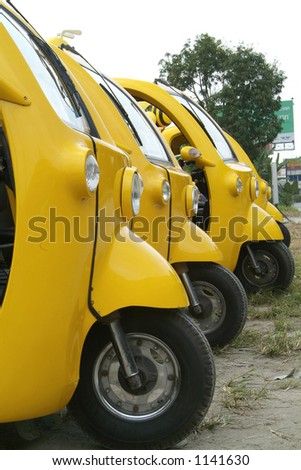 Yellow, three wheeled tuk-tuk vans in Bangkok, Thailand