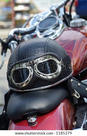 Leather motorcycle helmet with goggles on the seat of traditional, large motorcycle