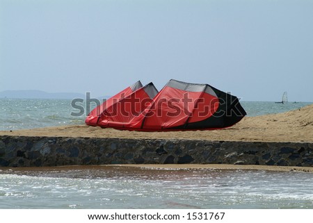 Red kite-surfer kite left on the beach