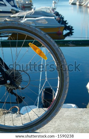 Part of bicycle wheel with boat harbour in the background. Boats intentionally out of focus.
