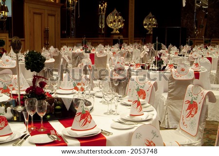 Tables prepared for a big party at a luxury hotel. Bibs and hats with crayfish motives.