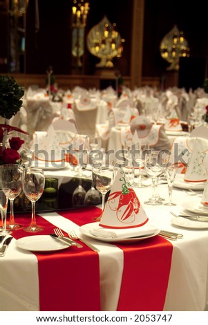 Tables decorated for a party at the ballroom of a luxury hotel. Bibs and hats with crayfish illustrations. Shallow depth of field.