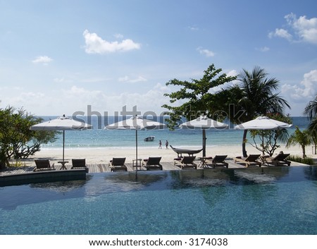 Swimming-pool near the beach at luxury, tropical resort hotel.