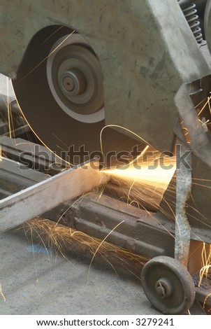 Rotating, industrial steel cutter in an industrial workshop with sparks flying.