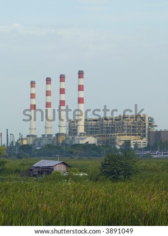 Gas driven power plant with four smoke stacks in a green field. Run-down shack in the foreground.