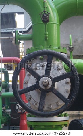 Large, industrial closing valve mounted on a green pipe for cooling liquids.