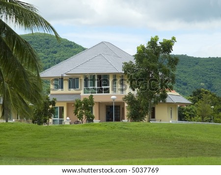 Modern style villa in lush, tropical setting. Forested hill in the background.