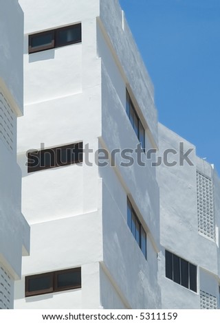Detail of facade at white apartment building with dark windows.
