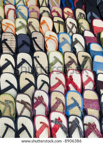 Lots of sandals in a market, many with Chinese style silk fabrics, all for the right foot.