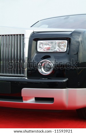 Black luxury car with chrome grill on a red carpet.