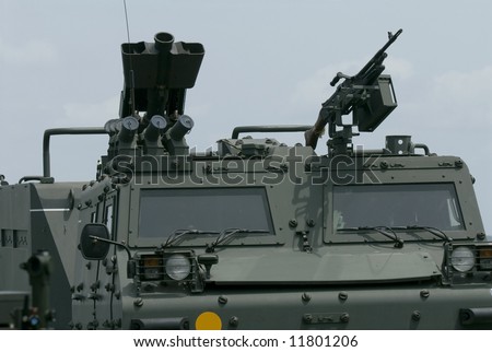 Front detail of tracked military vehicle with weaponry on the roof.