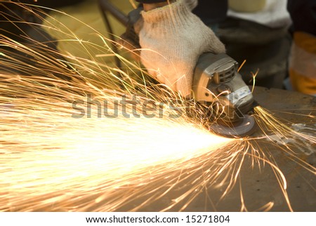 Angle grinder in use at a factory workshop. Slight motion blur on the grinder.