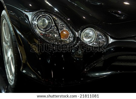 Front detail with headlights of black sports car.