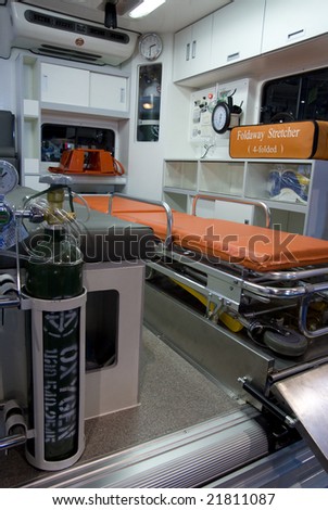 Interior of ambulance vehicle with stretcher and emergency equipment. Oxygen bottle in the foreground.