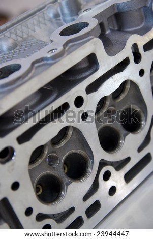 Detail of cast and milled iron engine block with four valves per cylinder. Shallow depth of field with parts of the engine out of focus.