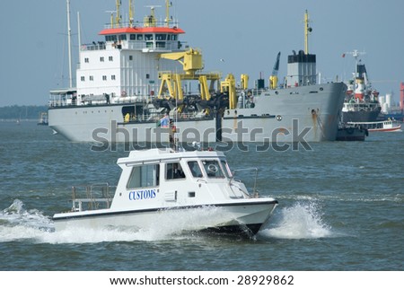 Boat from the customs department on its way to board a ship at an international port. Ship in the background out of focus.