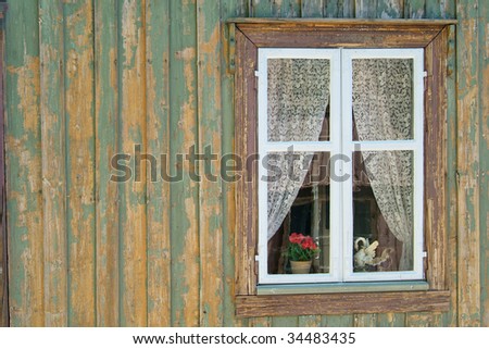 Window of old, wooden house where the paint is falling off the wall