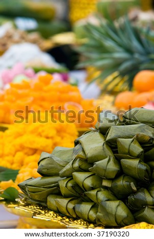 Thai sweets wrapped in pandanus leaves at a Buddhist temple ceremony in Thailand. Shallow depth of field with the nearest sweets in focus.