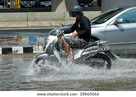 BANGKOK - AUGUST 14: Man on a scooter navigating through the flood after the heaviest monsoon rain in 20 years in the capital on August 14, 2009 in Bangkok, Thailand.