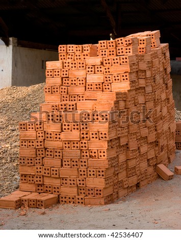 Stack of red bricks stored outdoor.