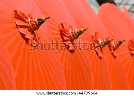 Orange cotton umbrellas at a handicraft festival in Bo Sang, Chiang Mai, Thailand. Shallow depth of field with the nearest umbrella in focus.