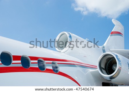 Rear detail of white and red, three engined corporate jet.