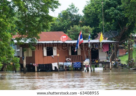House on stilts during monsoon season in Thailand, with water overflowing the area around and under the house.