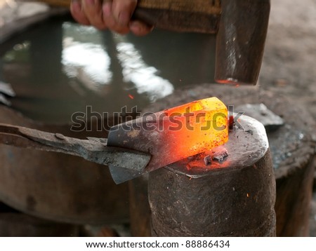 Blacksmith using a heavy hammer to forge an ax