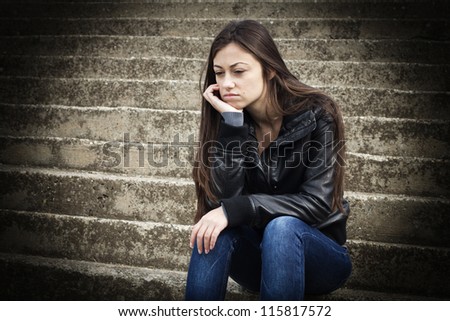 Portrait of depressed teenage girl sitting on staircase.