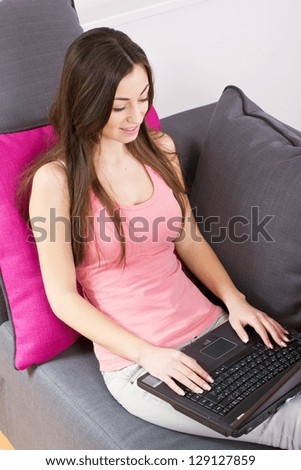 Tteenage girl relax on sofa using laptop at home.