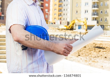 Construction manager looking project on building site .