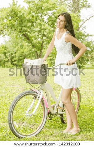 Attractive young woman with bicycle in the park at beautiful spring day.