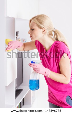 Young woman cleaning furniture at home.