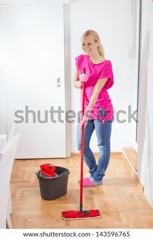 Young woman cleaning and mopping floor at home.