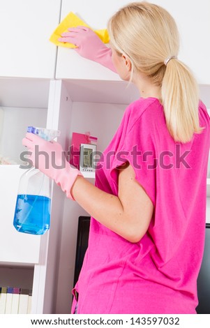 Young woman cleaning furniture at home.