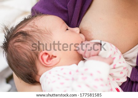 Mother breastfeeding newborn baby girl.