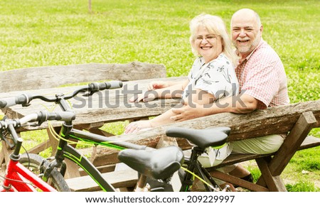 Happy elderly couple relaxing in the park after ride bike.