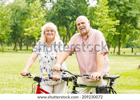 Happy elderly couple with bike in the park.
