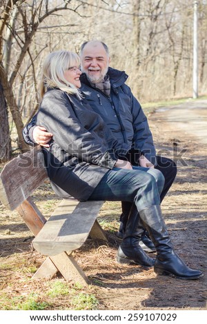Happy Elderly Senior Couple Relaxing in the nature. Old people sitting on the bench portrait outdoor winter autumn season.