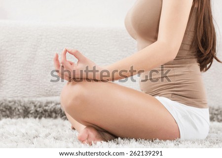 Young Woman Doing Yoga Meditating Relaxing Exercise at home.Healthy Lifestyle in Lotus Posture .Unrecognizable caucasian female practicing meditation on the floor.