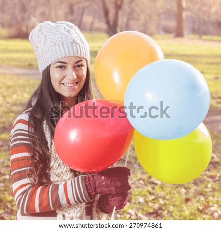 Happy Young Woman With Colorful Balloons at beautiful sunny autumn day. Carefree Female lifestyle scene.