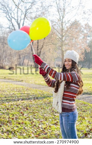Happy Young Woman With Colorful Balloons at beautiful sunny autumn day. Carefree Female lifestyle scene.