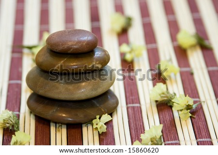 Zen like balanced stones and dried flower on bamboo background.