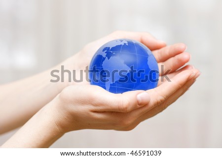 Blue transparent earth globe in the hand with shallow DOF.