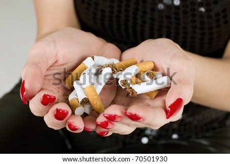Female hands holding broken cigarette.