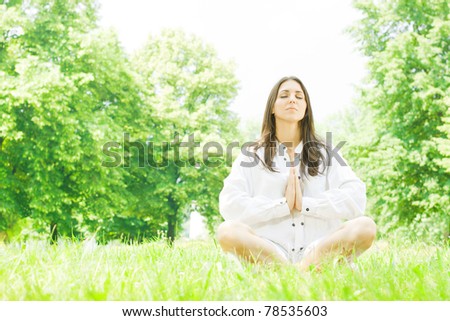 Beautiful young woman in meditation pose outdoors.