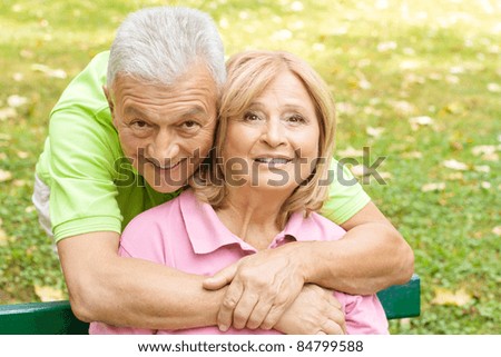 Portrait of a happy senior man embracing her wife in the park.
